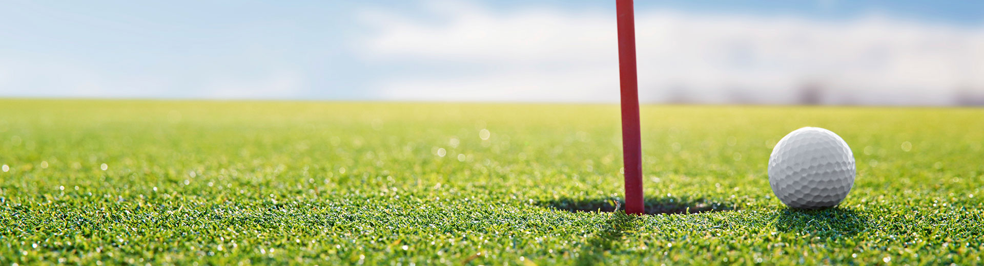 golf course with flagpole and golf ball near hole